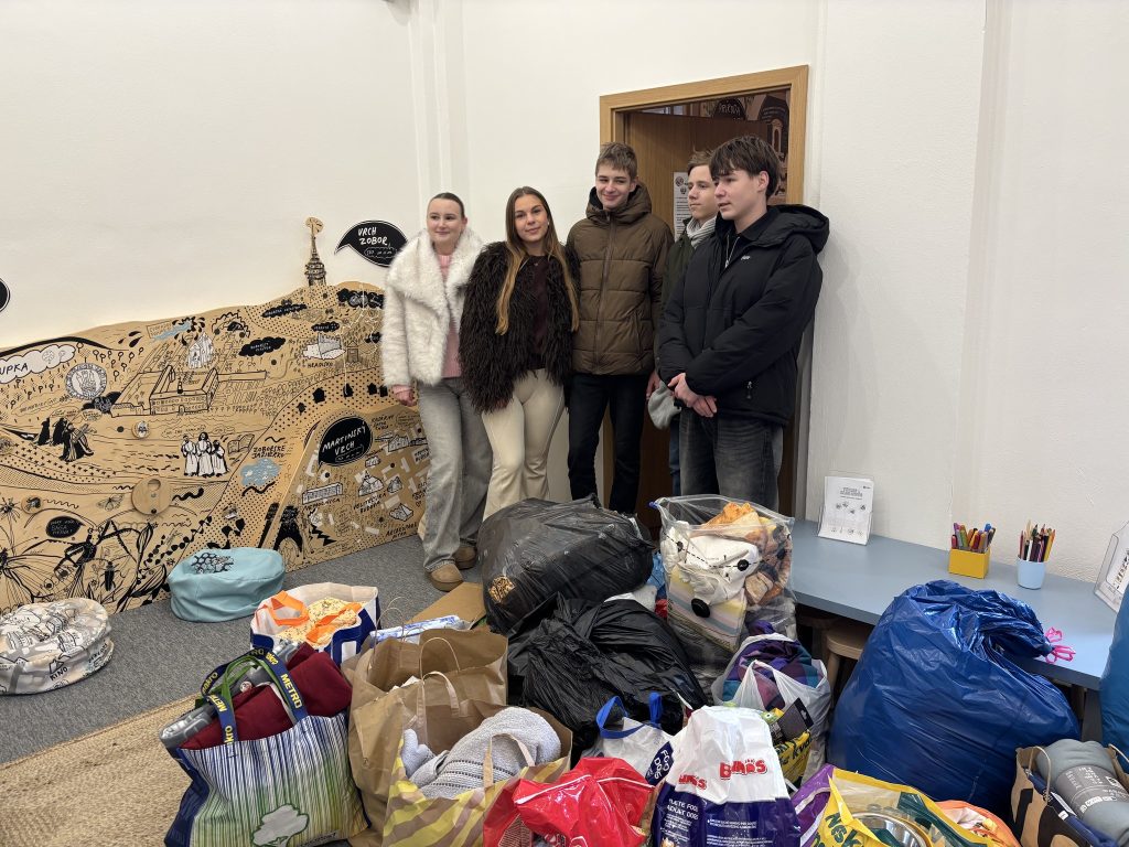 nazbierané veci v popredí a v pozadí niekoľko ľudí, ktorí sa zapojili do zbierky pre zvieratá